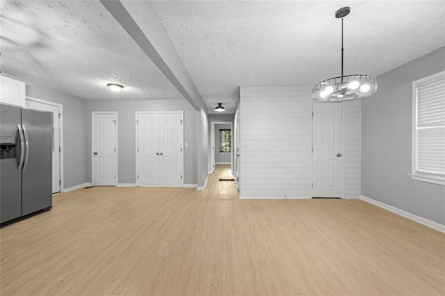 interior space with a chandelier, a textured ceiling, and light wood-type flooring