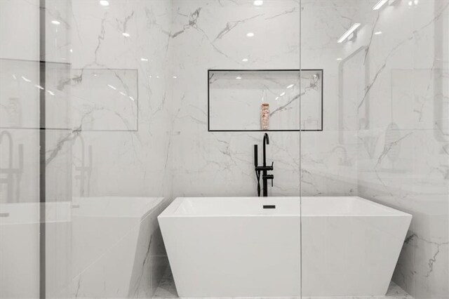 bathroom with a bathing tub and tile walls