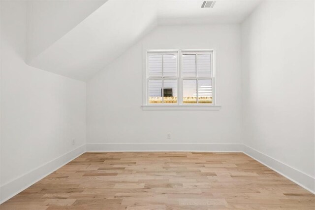 bonus room with light wood-type flooring and vaulted ceiling