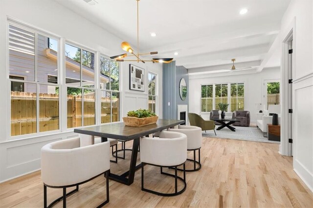 dining area featuring beam ceiling, light hardwood / wood-style flooring, and ceiling fan with notable chandelier