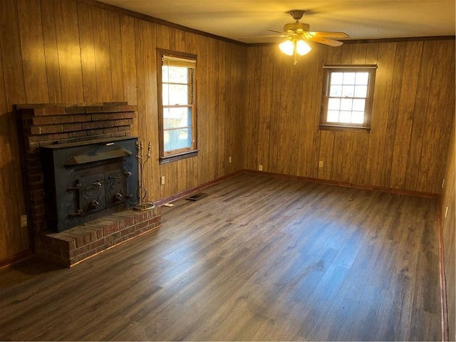 unfurnished living room featuring dark hardwood / wood-style flooring, crown molding, wooden walls, and ceiling fan