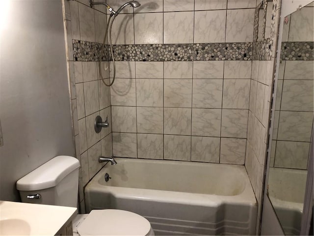 full bathroom featuring tiled shower / bath, vanity, and toilet