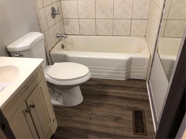 full bathroom with vanity, wood-type flooring, tiled shower / bath, and toilet