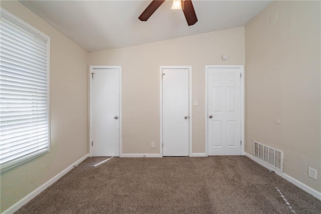 unfurnished bedroom with vaulted ceiling, carpet, visible vents, and baseboards