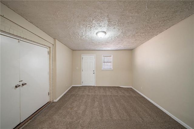 carpeted foyer with a textured ceiling and baseboards