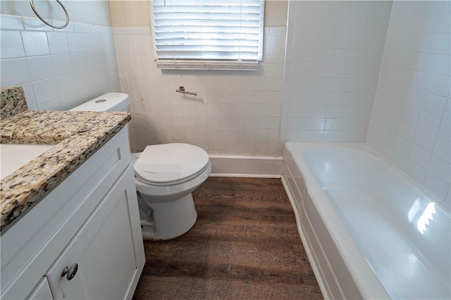 full bath with toilet, wood finished floors, vanity, and tile walls