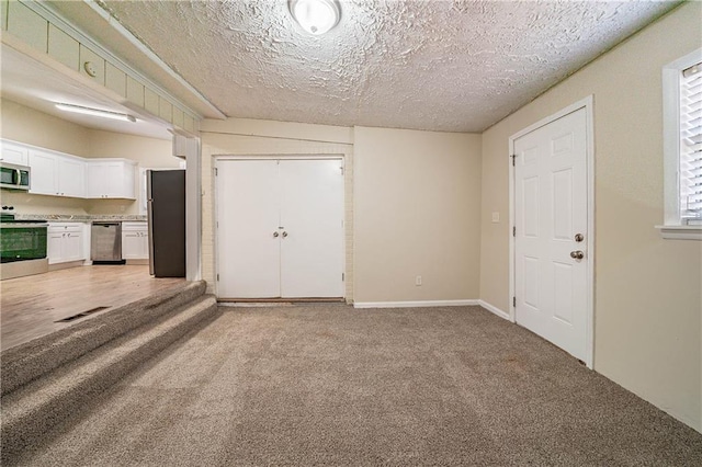 interior space with light carpet, a textured ceiling, visible vents, and baseboards