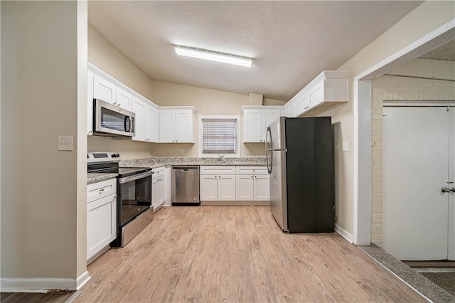 kitchen with stainless steel appliances, a sink, white cabinetry, light wood-style floors, and vaulted ceiling