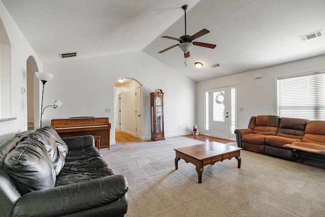 carpeted living room with ceiling fan and lofted ceiling