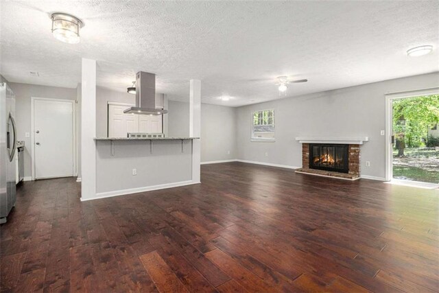 1781 Jajef Ave, Conley, GA 30288 - unfurnished living room with baseboards, a brick fireplace, a textured ceiling, and dark wood-type flooring