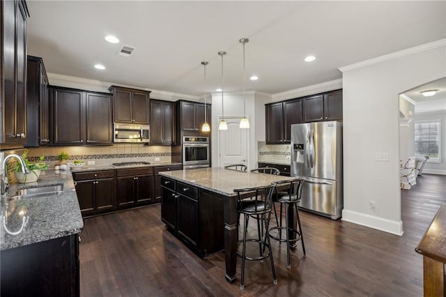 3610 Ansley Manor Ct, Cumming, GA 30028 - kitchen featuring appliances with stainless steel finishes, a sink, ornamental molding, light stone counters, and a center island