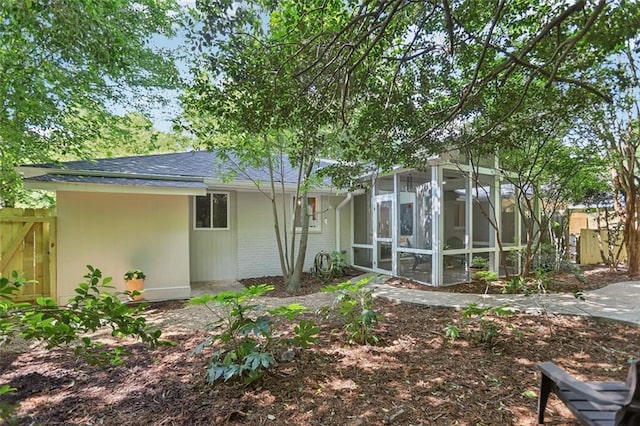 rear view of house featuring a sunroom and fence