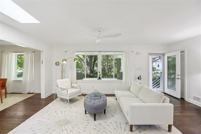 living area featuring baseboards, a wealth of natural light, a skylight, and wood finished floors