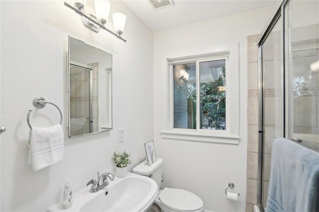 bathroom featuring a sink, toilet, an enclosed shower, and visible vents