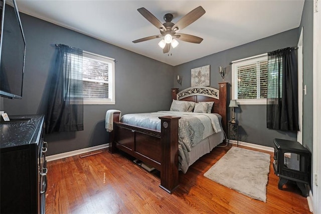 57 Jonathan Rd, Riverdale, GA 30274 - bedroom featuring wood finished floors, baseboards, a wood stove, and a ceiling fan