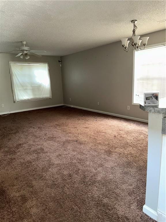 carpeted empty room with a textured ceiling and ceiling fan with notable chandelier