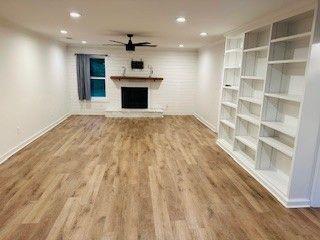 1360 Bethany Ct, Alpharetta, GA 30004 - unfurnished living room featuring ceiling fan, wood finished floors, a fireplace with raised hearth, and recessed lighting