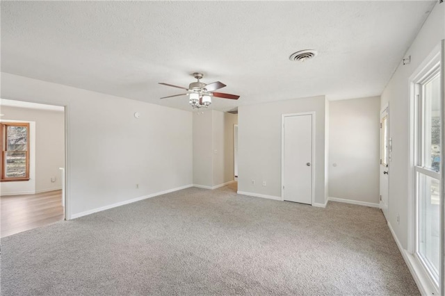 carpeted empty room featuring visible vents, a healthy amount of sunlight, and a textured ceiling