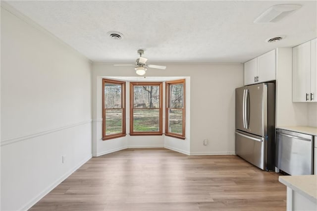 kitchen with visible vents, light countertops, light wood-style flooring, stainless steel appliances, and white cabinetry