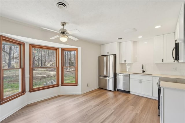 kitchen featuring visible vents, light wood-style flooring, a sink, stainless steel appliances, and light countertops