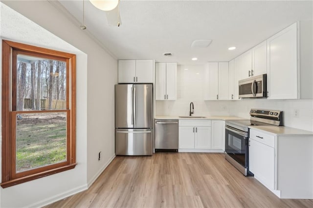 kitchen with a sink, tasteful backsplash, appliances with stainless steel finishes, and white cabinetry