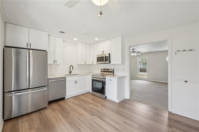 kitchen with a sink, white cabinetry, appliances with stainless steel finishes, and light countertops