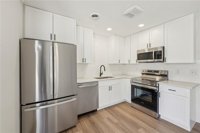 kitchen with visible vents, appliances with stainless steel finishes, white cabinetry, and a sink