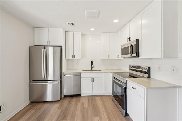 kitchen with visible vents, backsplash, light wood-style floors, stainless steel appliances, and a sink