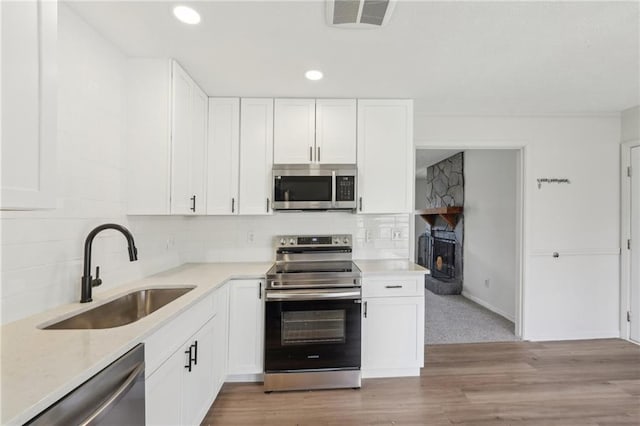 kitchen featuring tasteful backsplash, visible vents, appliances with stainless steel finishes, white cabinetry, and a sink