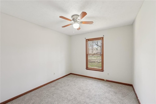 spare room featuring a textured ceiling, a ceiling fan, baseboards, and light carpet