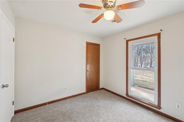 unfurnished room featuring a ceiling fan, light colored carpet, and baseboards