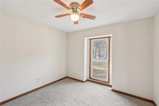 spare room featuring baseboards, light colored carpet, and ceiling fan