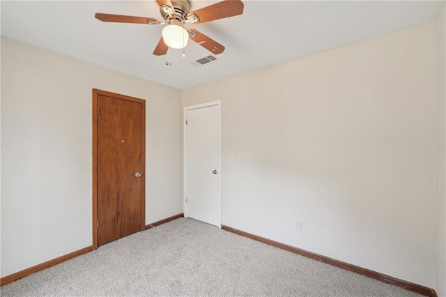 carpeted spare room with visible vents, ceiling fan, and baseboards