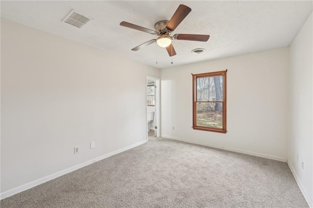 carpeted spare room featuring visible vents, baseboards, and ceiling fan