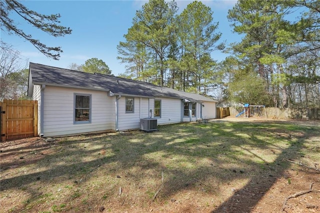 back of property with a playground, a yard, fence, and central AC