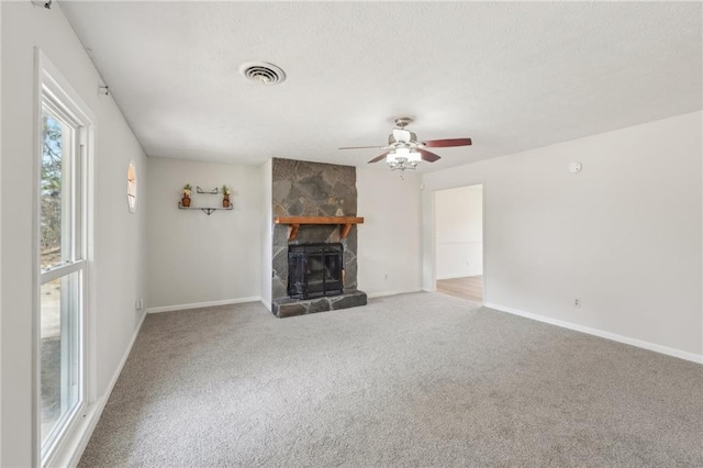 unfurnished living room featuring a stone fireplace, carpet flooring, visible vents, and a textured ceiling