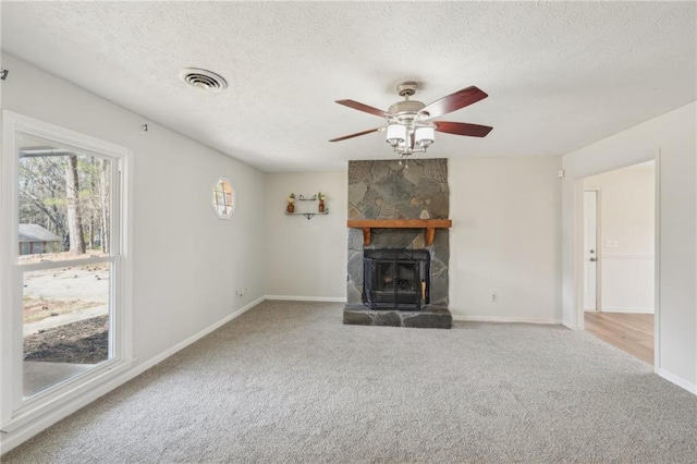 unfurnished living room with visible vents, carpet floors, a textured ceiling, and a fireplace