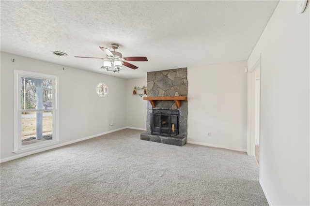 unfurnished living room with visible vents, carpet floors, a textured ceiling, and a stone fireplace