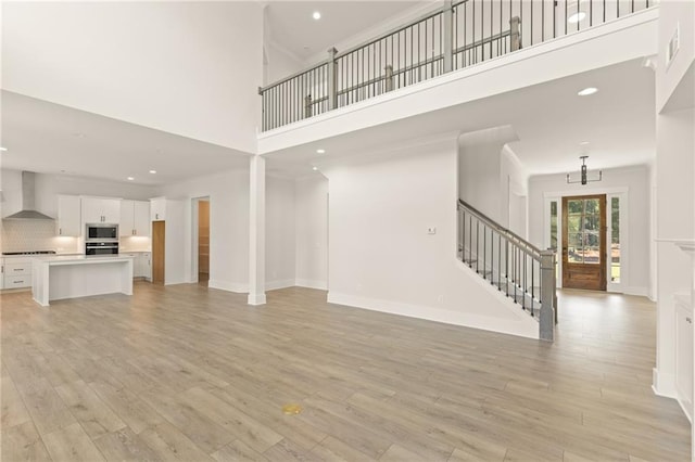 unfurnished living room with a high ceiling and light hardwood / wood-style floors