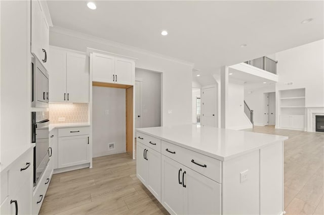 kitchen with appliances with stainless steel finishes, white cabinets, backsplash, and crown molding