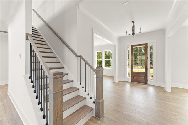 entrance foyer featuring ornamental molding, light wood-type flooring, and an inviting chandelier