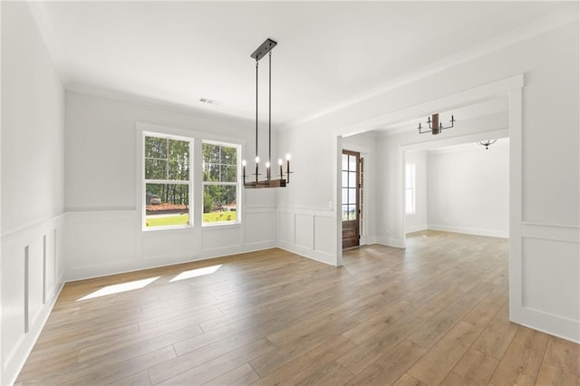 unfurnished dining area with light wood-type flooring, a notable chandelier, and ornamental molding