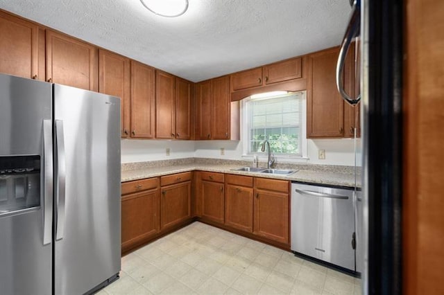 kitchen with appliances with stainless steel finishes, brown cabinets, light countertops, and a sink