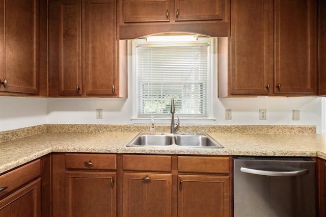 kitchen with a sink, brown cabinetry, light countertops, and dishwasher