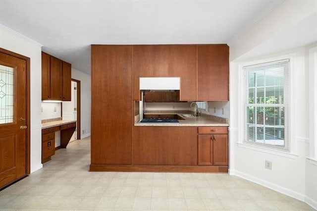 kitchen featuring light countertops, black gas stovetop, brown cabinets, and baseboards