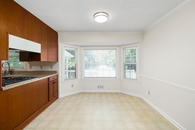 kitchen featuring ornamental molding, light countertops, stainless steel gas cooktop, and baseboards