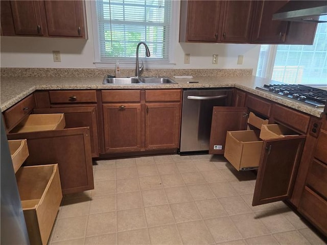 kitchen with stainless steel appliances, a sink, wall chimney range hood, and light stone counters