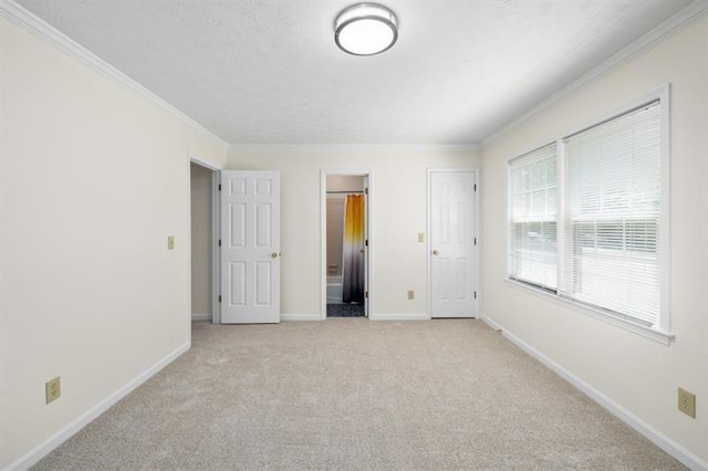 unfurnished bedroom with light colored carpet, ornamental molding, a textured ceiling, ensuite bath, and baseboards