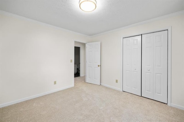 unfurnished bedroom with a closet, light colored carpet, crown molding, and baseboards