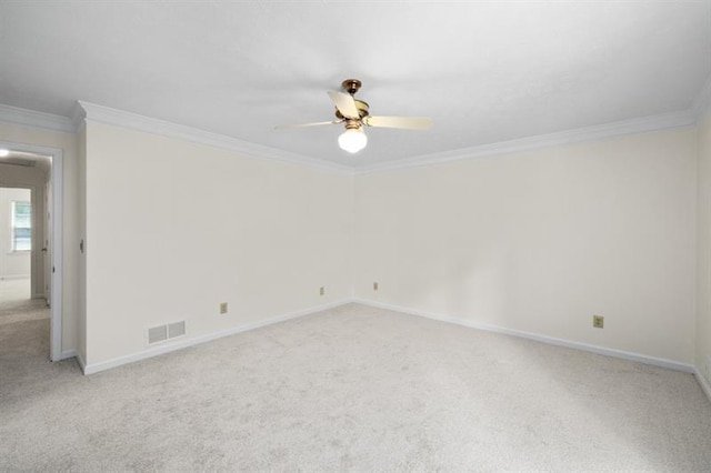 empty room with visible vents, ornamental molding, a ceiling fan, light carpet, and baseboards